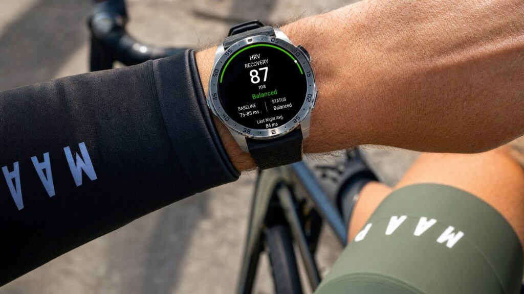 Cyclist's wrist wearing a premium sports smartwatch displaying HRV recovery score