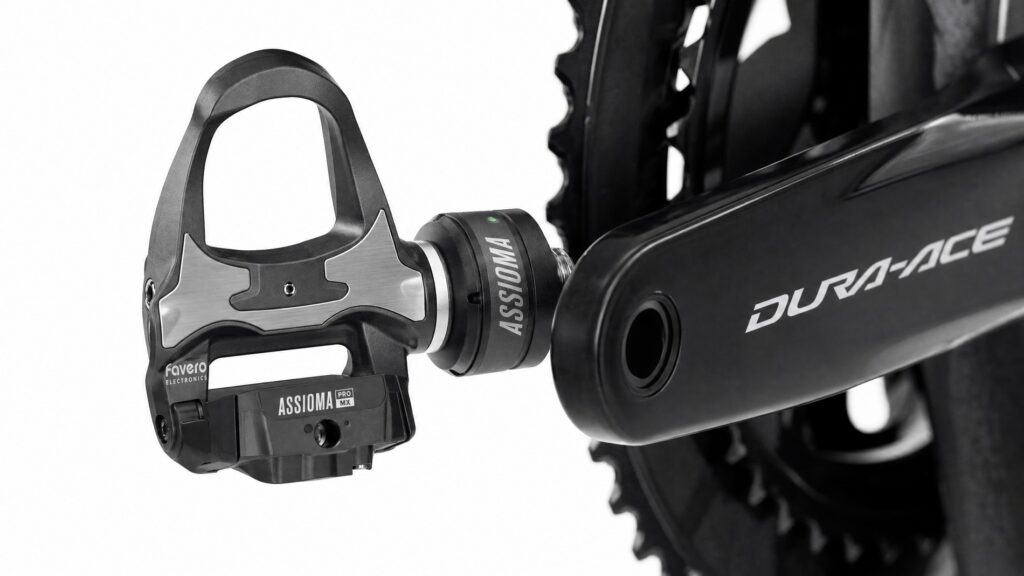 High-tech dual-sided cycling power meter pedal installed on a black carbon road bike crank arm