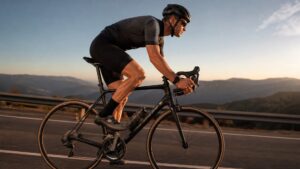 Road cyclist riding efficiently on a paved mountain road with hills and sunset lighting